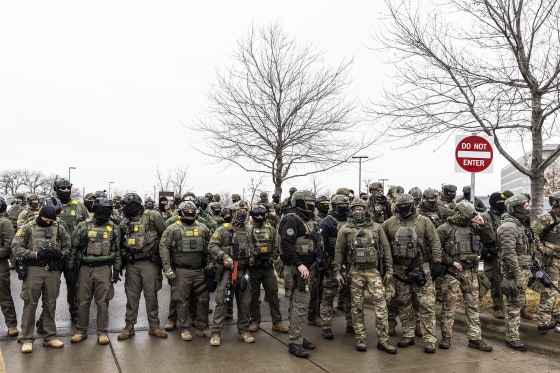 Federal Agents stand guard outside an ICE facility during a protest following the fatal shooting of Renee Good. 