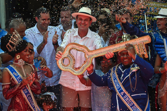 Agroup of people gather to celebrate canival in Brazil while confetti is thrown out.