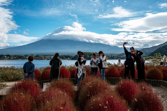 Image: Tourists take pictures as cloud-clad Mount Fuji is seen in the background