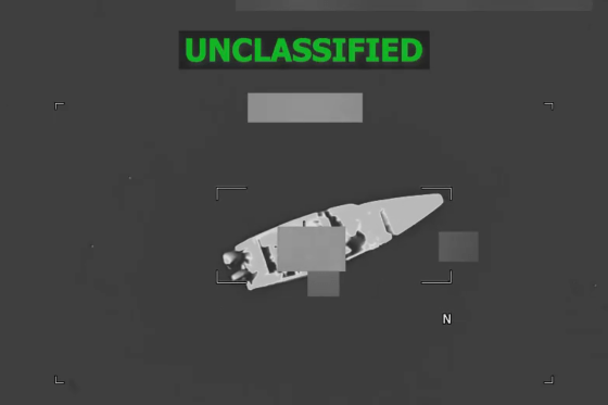 A black and white aerial view of a boat on the water, green text at the top reads "unclassified"