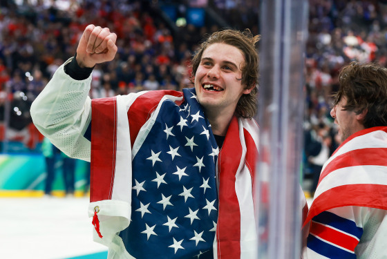 Jack Hughes of Team United States celebrates after their gold-medal win with an American flag draped over his back