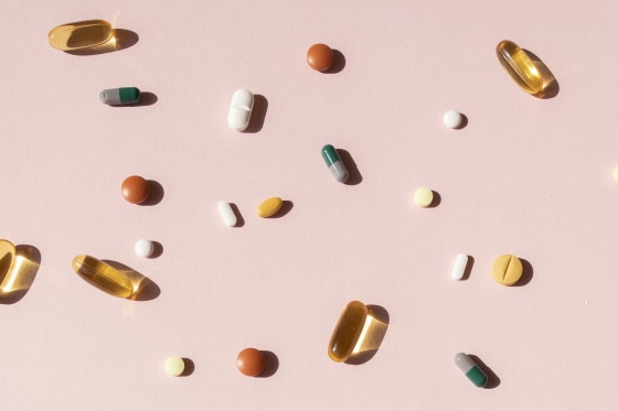 Top view of various pills and tablets on the pink background