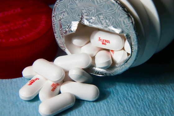 White tylenol pills lie outside a bottle tipped on its side.