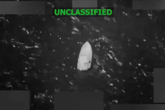 A grainy black-and-white still image taken from video shows a boat floating in the water.