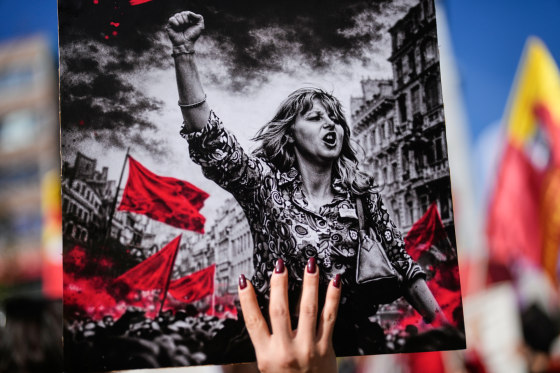 A hand holds up a poster of a woman raising a fist