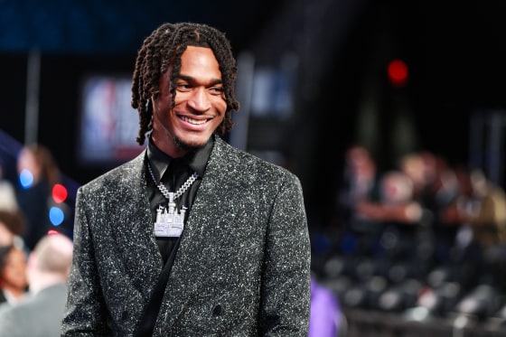 Stephon Castle smiles, wearing a diamond chain with a castle pendant, and a glittery black suit