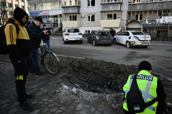 Residents look at a crater as police expert work at a site of a strike in the town of Brovary, near Kyiv, following a Russian missile and drone attack, on March 14.