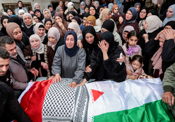 Mourners react as they carry the wrapped bodies of a Palestinian family