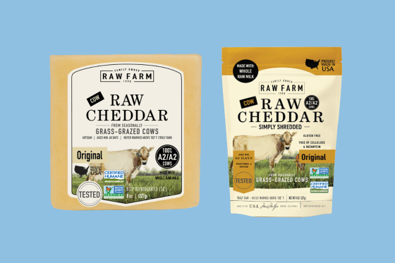 A photo illustration showing Raw Farm Raw Cheddar Cheese packaging and shredded cheese packaging next to one another on top of a blue background