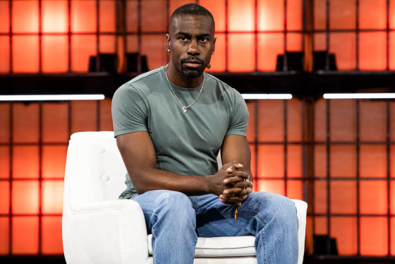 Deray Mckesson sits on a white couch on stage