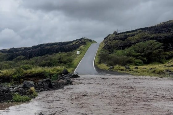 A view of flood waters in the front of a hilly road and grassy planes