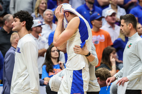 A basketball player hides his head inside his jersey while walking on the court.