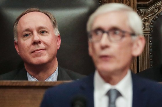 Robin Vos, left, sits behind Tony Evers, who blurred in the foreground