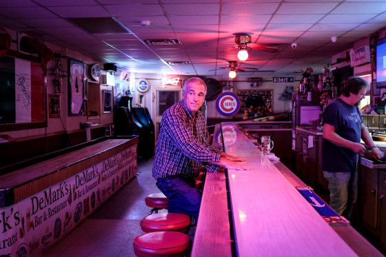 Harry Wait sits at a bar, the mood lighting is pink