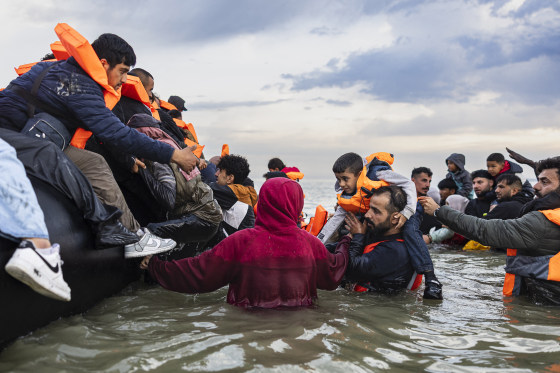 People try to board a smuggler's boat in an attempt to cross the English Channel off the beach of Gravelines, northern France on August 12.