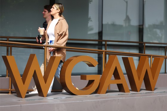 People walk past the WGAW logo displayed outside Writers Guild of America West headquarters.