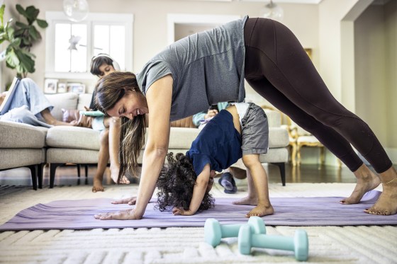 Mother exercising at home while distracted by toddler boy