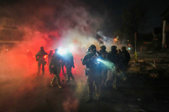 Image: Law enforcement officers stand amid tear gas at the scene of a reported shooting in Minneapolis