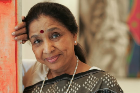 Asha Boshe leans up against an entryway and smiles for a portrait