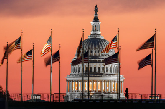 U.S. Capitol Dome at Sunrise, multiple flags wave atop flag poles surrounding the dome