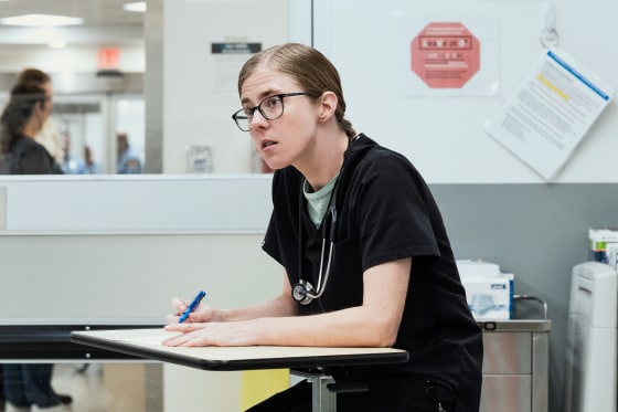 Taylor Dearden sits at a desk holding a pen