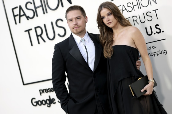Dylan Sprouse and Barbara Palvin stand for photos in front of a step-and-repeat backdrop.