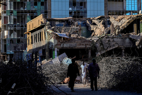 Sudanese men walk past destroyed building in the capital Khartoum.