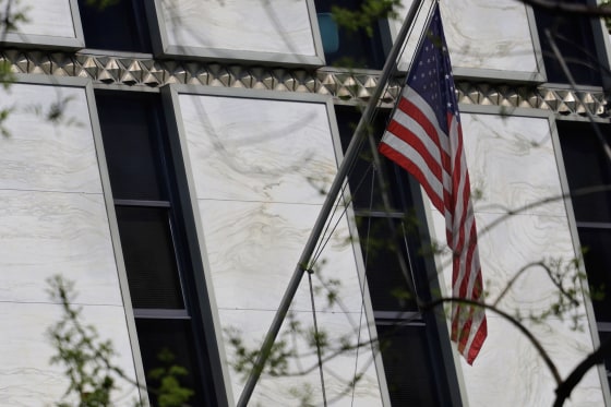 The American flag is displayed outside a non-descript marble building with slender tinted windows.