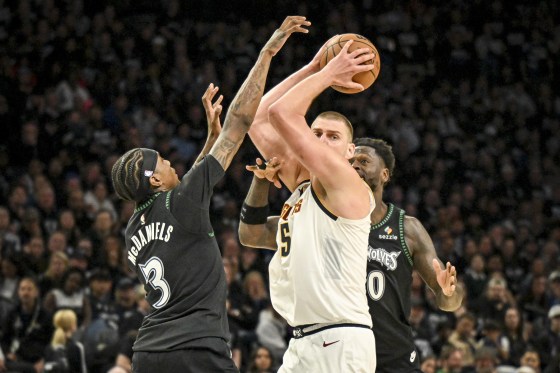 Jaden McDaniels and Julius Randle of the Minnesota Timberwolves mob Nikola Jokic of the Denver Nuggets