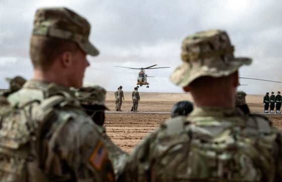 Soldiers look at a plan taking off in the distance outside