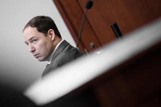 A tilted view of Brendan Banfield, seated in a courtroom.