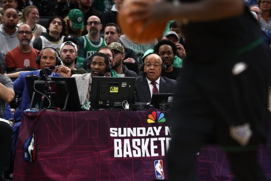 Three NBC sportscasters seated courtside during a basketball game.