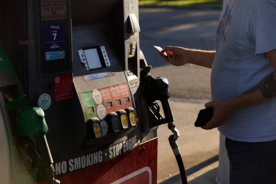 A person prepares to insert their credit card into a card reader at a gas station pump