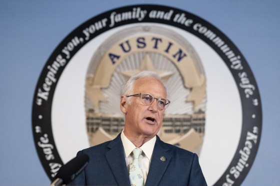 Kirk Watson speaks during a press conference in front of the seal of the AUstin Police Department.