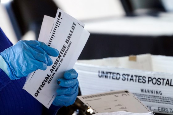 Two gloved hands hold absentee ballots