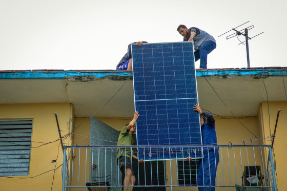 Solar panel specialists lift a panel onto the rooftop of a multi-family building in Matanzas, Cuba, on April 13, 2026. 