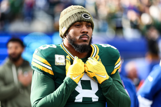 Josh Jacobs of the Green Bay Packers holds his collar while standing on the field outside