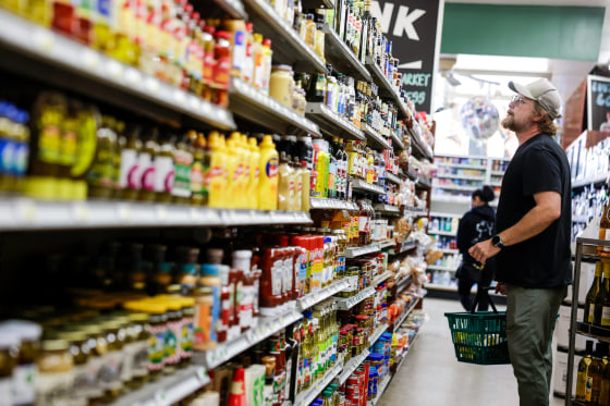 A customer looks up at food products in a grocery aisle