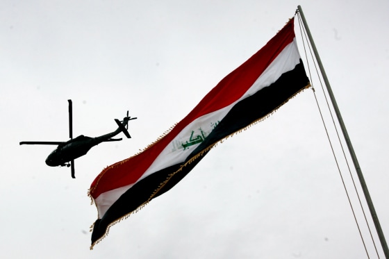 A U.S Army helicopter flies over an Iraqi flag