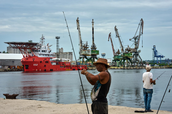 A fisherman prepares his fishing rod in front of the Colombian Navy ship ARC Carib in Havana.