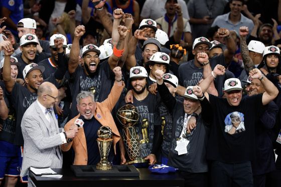 New York Knicks players celebrate while standing with their coach during an after-game press conference.