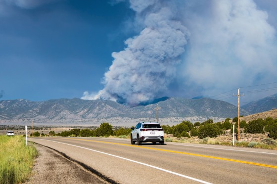 A vehicle travels toward thick smoke rising from the Iron Fire burning in the East Tintic Mountains
