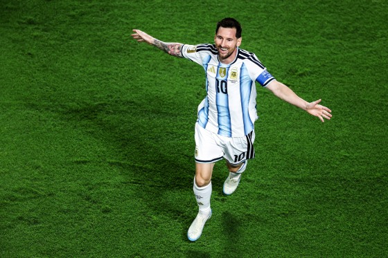 Lionel Messi runs on the soccer field with his arms outstretched in celebration