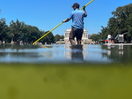 A U.S. National Park Service employee uses a vacuum pump to clean algae off the bottom of the newly repainted Lincoln Memorial Reflecting Pool on the National Mall