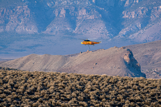 A firefighting helicopter flies over the mountain landscape near Piute Reservoir.