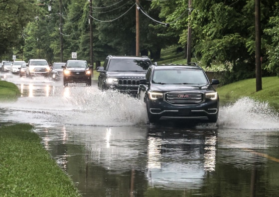A line of vehicles driving through floodwater.