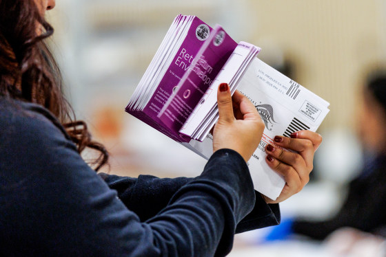 Vote by Mail ballots are inspected by a worker who flips through the envelope