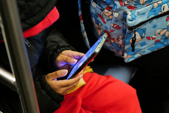 A young boy plays a video game on a smartphone .