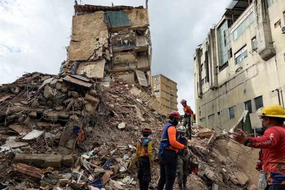 Workers search for people amongst the rubble of an apartment building