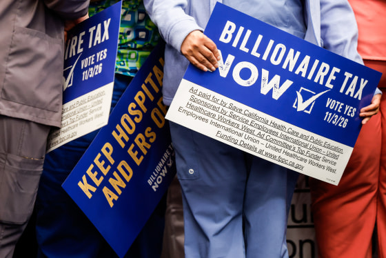 People hold signs calling for a billionaire tax